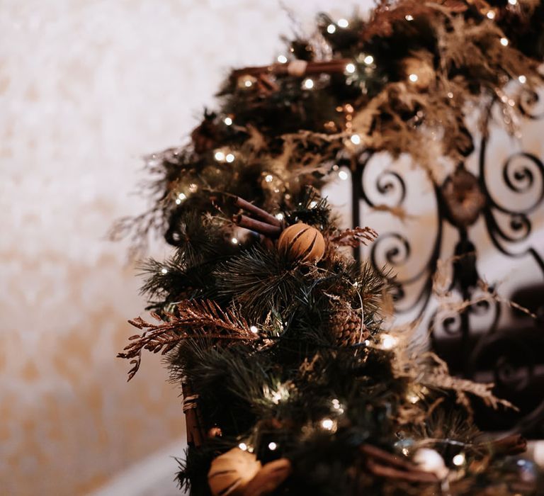 Festive winter wedding garland with cinnamon sticks, dried oranges and fairy lights 