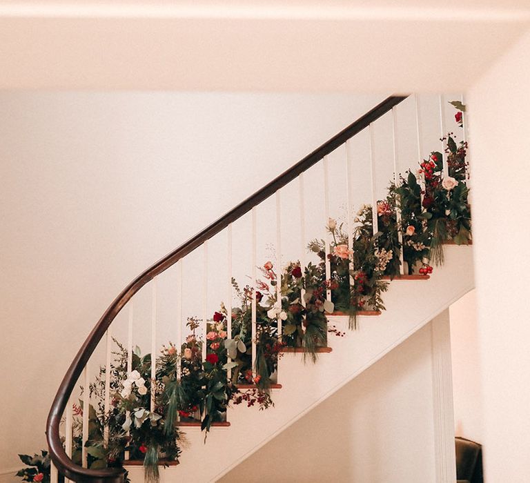 Festive red Christmas wedding flowers decorating the staircase at Aswarby Rectory in Lincolnshire 