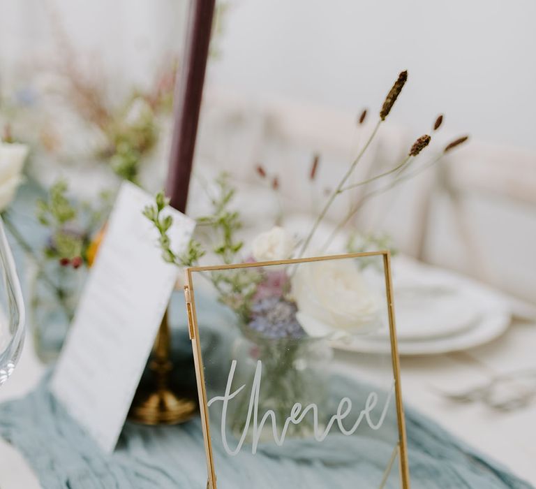 Gold frame wedding table number sign on dusty blue table runner