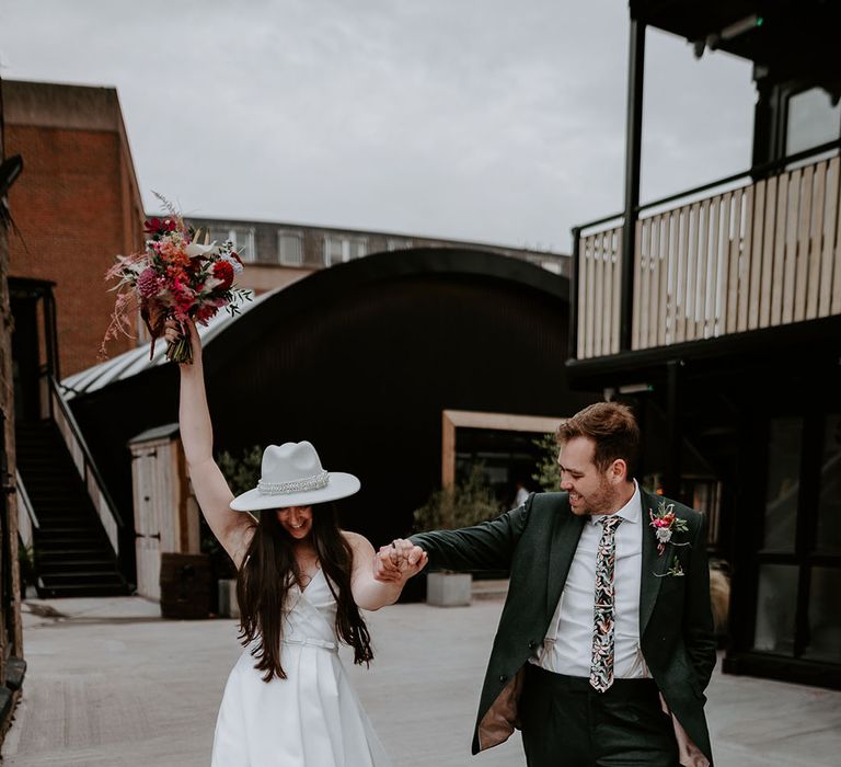 Groom in green suit with jungle tie with the bride wearing white pearl bridal hat 