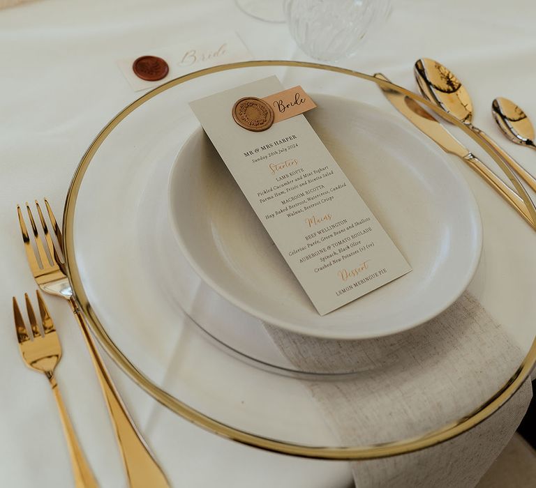 Gold charger plate with gold cutlery, white plates and white wedding menu stationery 