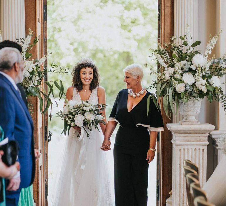 Mother of the bride in a black and white jumpsuit walking bride down the aisle 