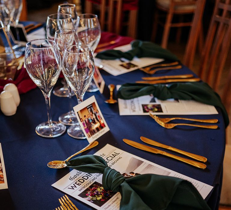 Sapphire wedding table cloth for jewel tone colour palette wedding with gold cutlery, wedding newspapers and Polaroid place names 