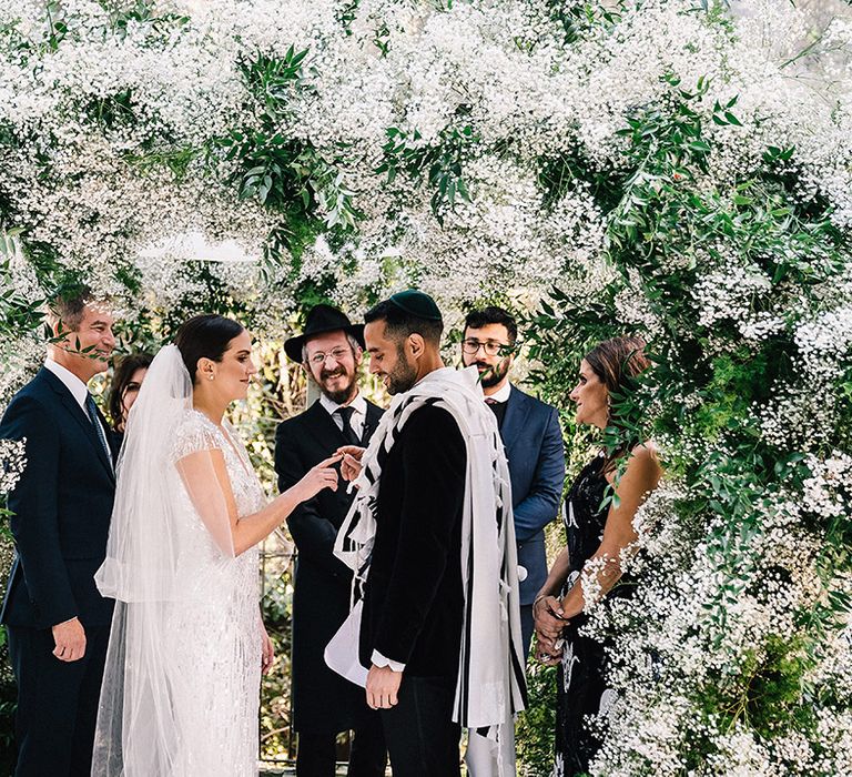 The bride and groom participate in their Jewish wedding ceremony conducted by a rabbi 