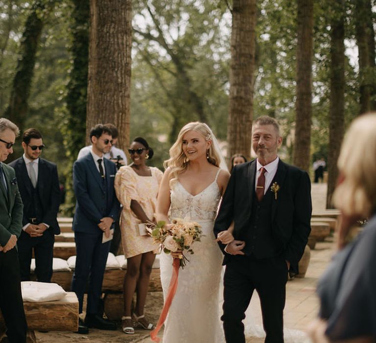 Father of the bride walks bride down the aisle at boho destination outdoor wedding 