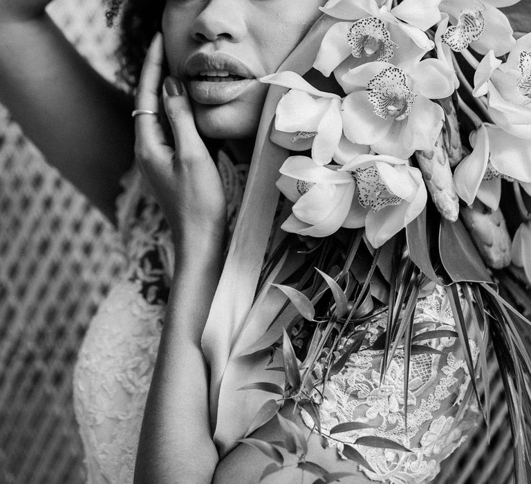 Bride touches face and holds jungle themed bouquet from Southwold Flower Co