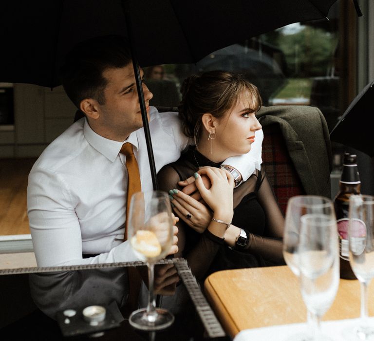 Groom puts his arm around bride during wedding speeches