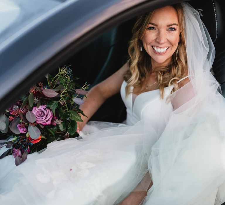 Bride smiles and laughs in the car on her wedding day 