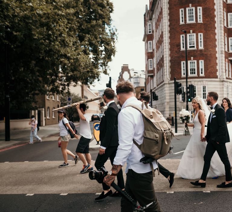 Bride & groom walk through the streets of London with wedding party