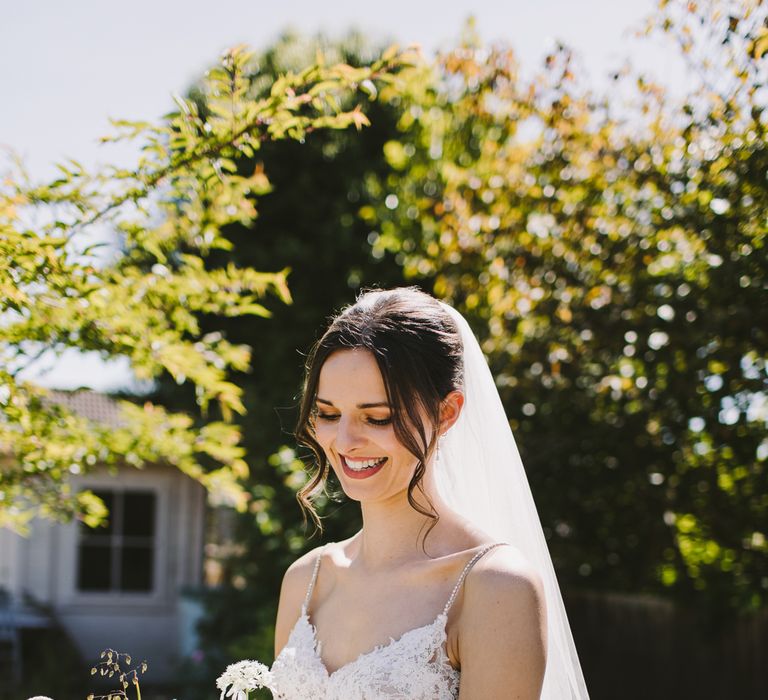 Dark haired bride wears Enzoani wedding gown carrying dark and white floral bouquet