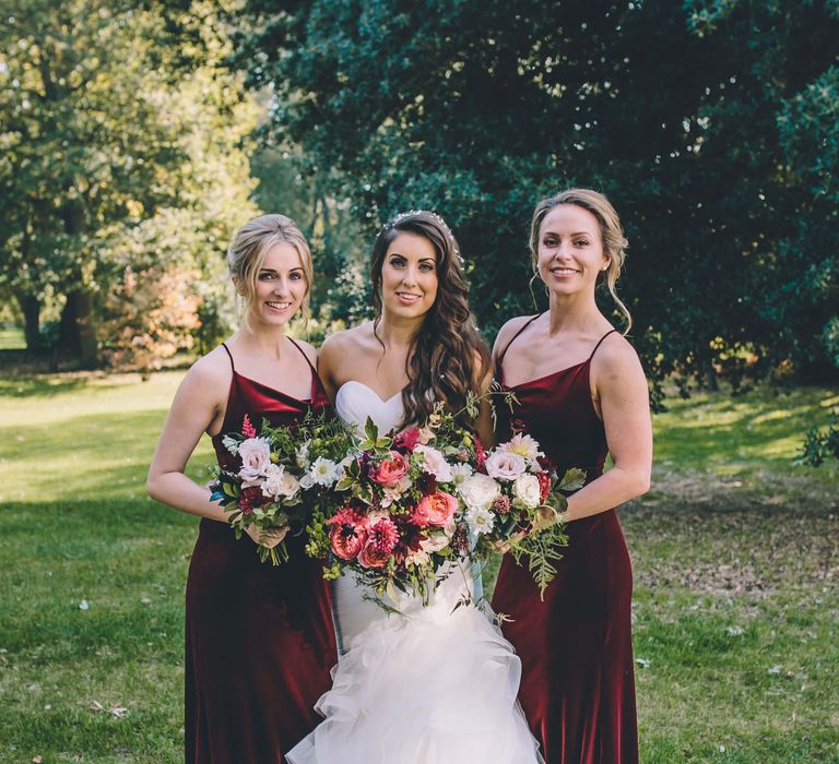 Bride with two bridesmaids with red bridesmaid dresses and bright pink flowers 