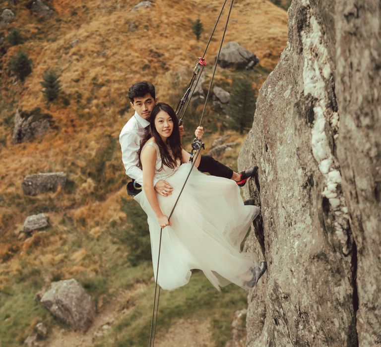 Couple embrace during engagement session with countryside surrounding them