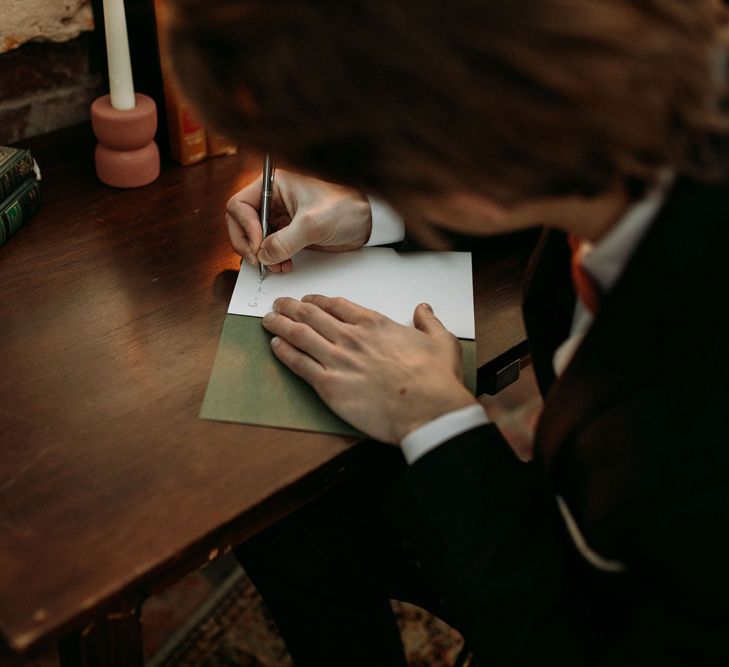 Groom writing his wedding vows in a booklet