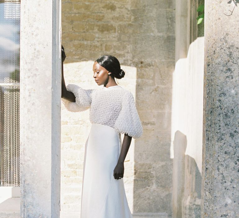 Bride is wearing a puff sleeve and pearl top detailing wedding dress by Romancera Madrid