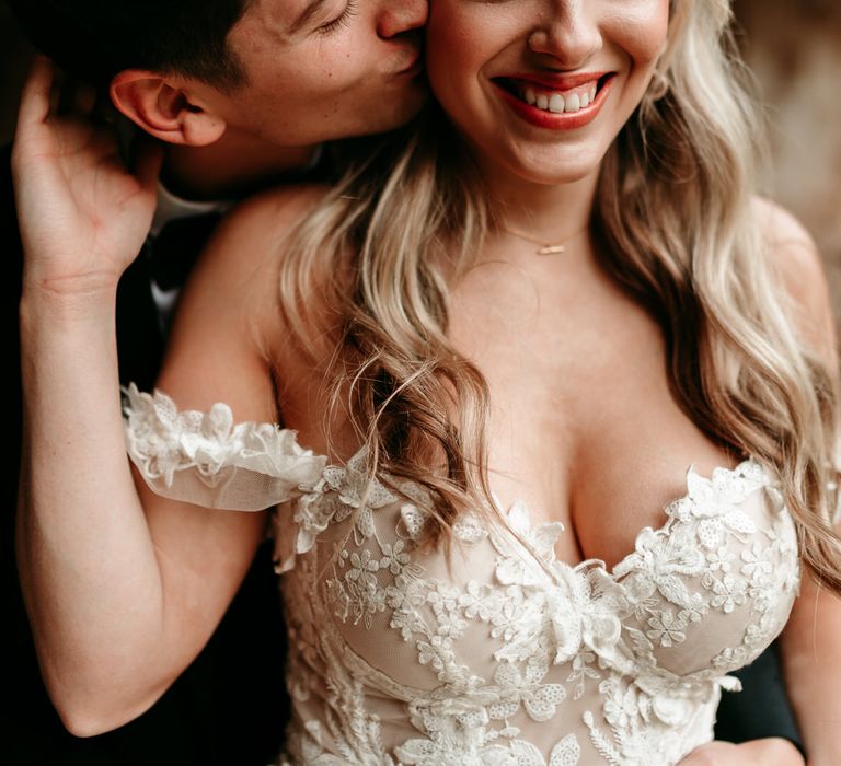 Bride in appliqué off the shoulder wedding dress with coral lipstick