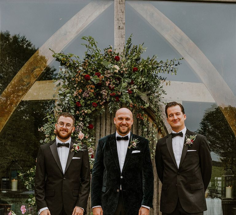 Groom in a velvet tuxedo jacket and groomsmen in black tuxedos 