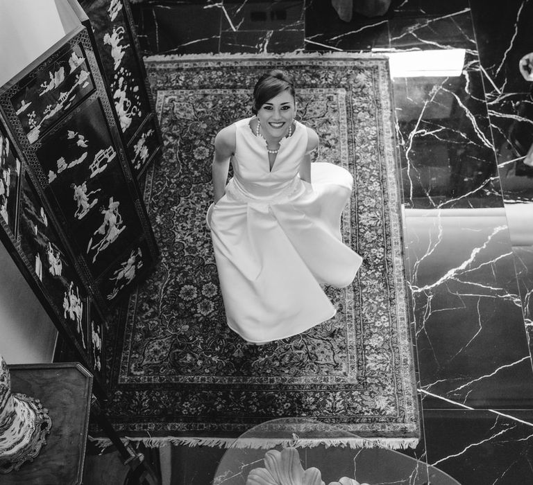 Bride seen from above, looking at the camera with her hands in her wedding dress pockets