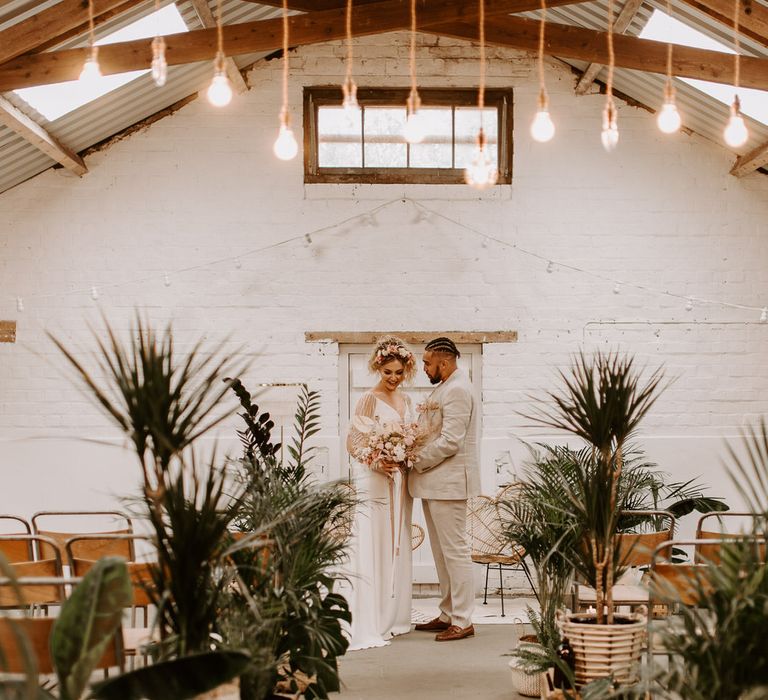 Bride and groom at the altar in industrial style building with tropical plants