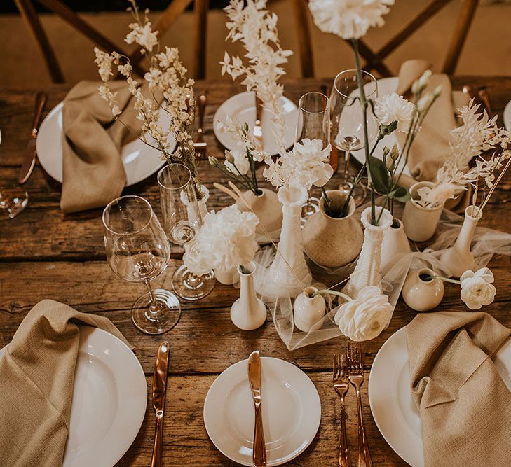 Small beige and white vases with dried flower stems wedding table decor 