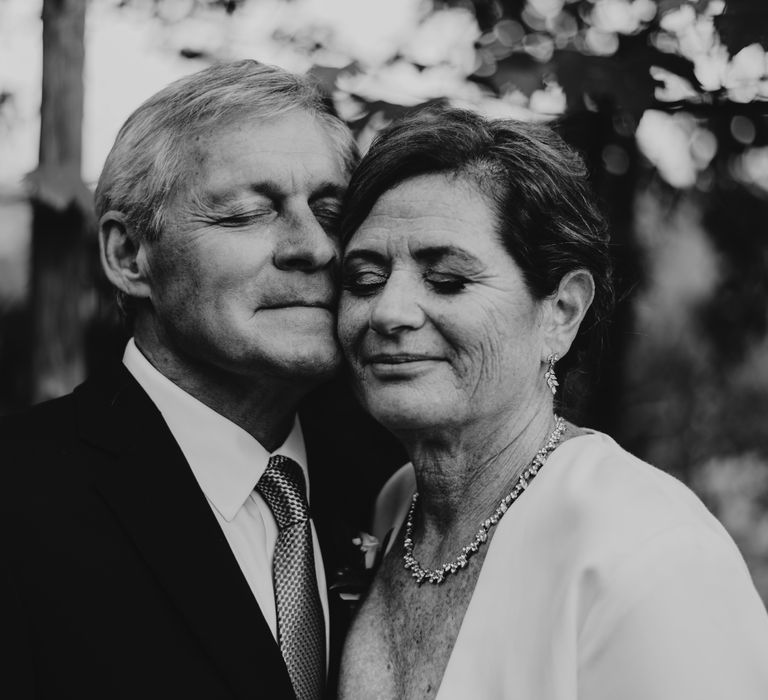 Black & white image of bride & groom holding their heads against one another's on their wedding day