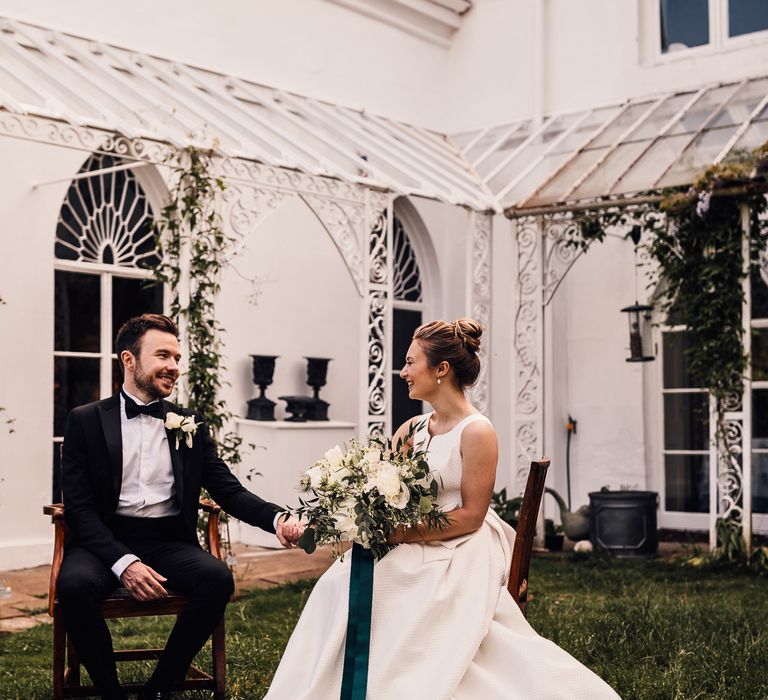 Bride & groom sit outdoors for English country wedding