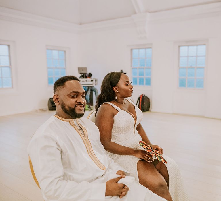 Bride & groom sit with one another in their reception outfits on wedding day 