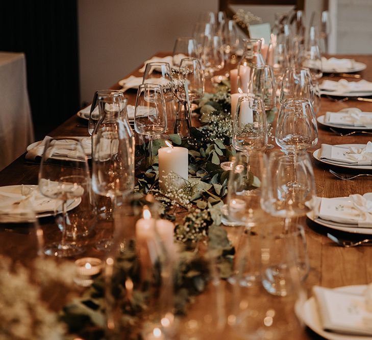 Intimate wedding reception table decor with foliage table runner and pillar candles 