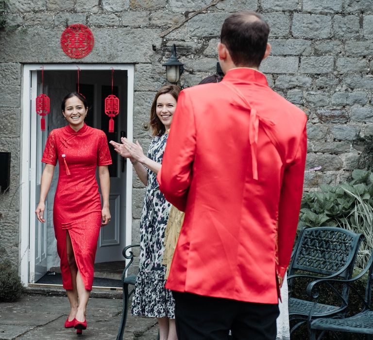 Bride wears traditional Chinese Tea Ceremony dress in red whilst leaving to greet her groom