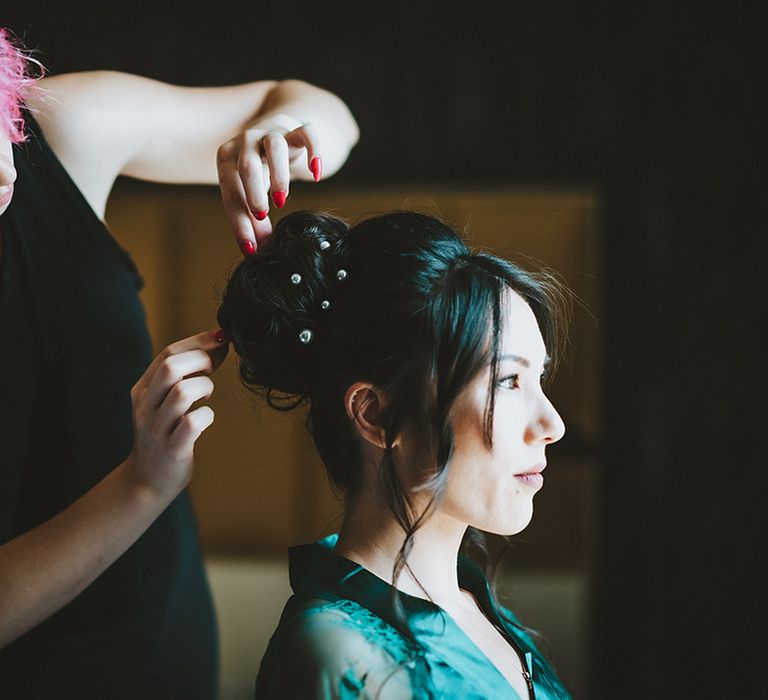 East Asian bride has her hair done on the morning of her wedding day in up-do with curled strands