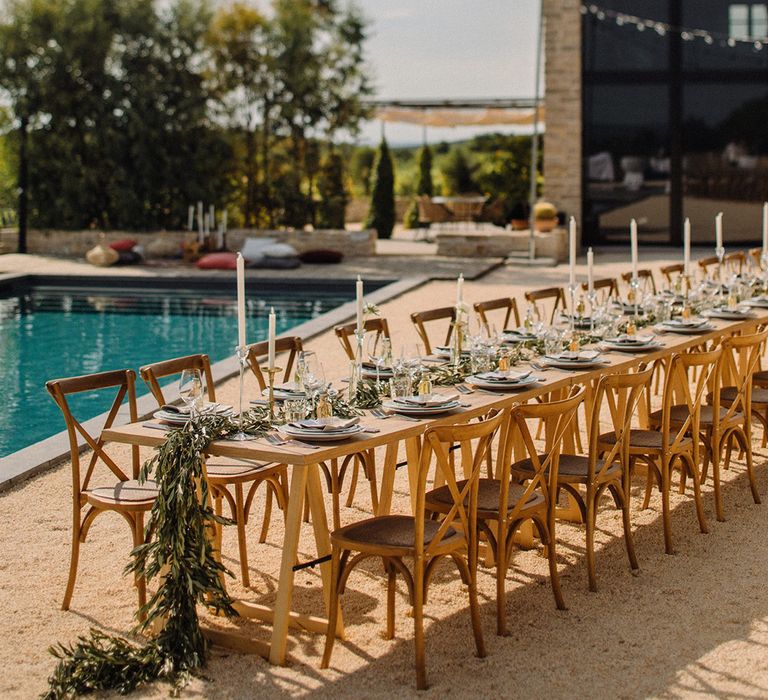 Rustic Villa complete with swimming pool and wooden table for reception finished with olive branch table runner and delate white florals throughout