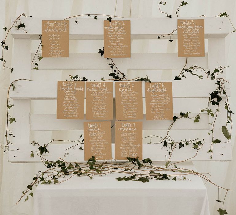 DIY table plan complete with brown stationery and silver writing with green foliage 