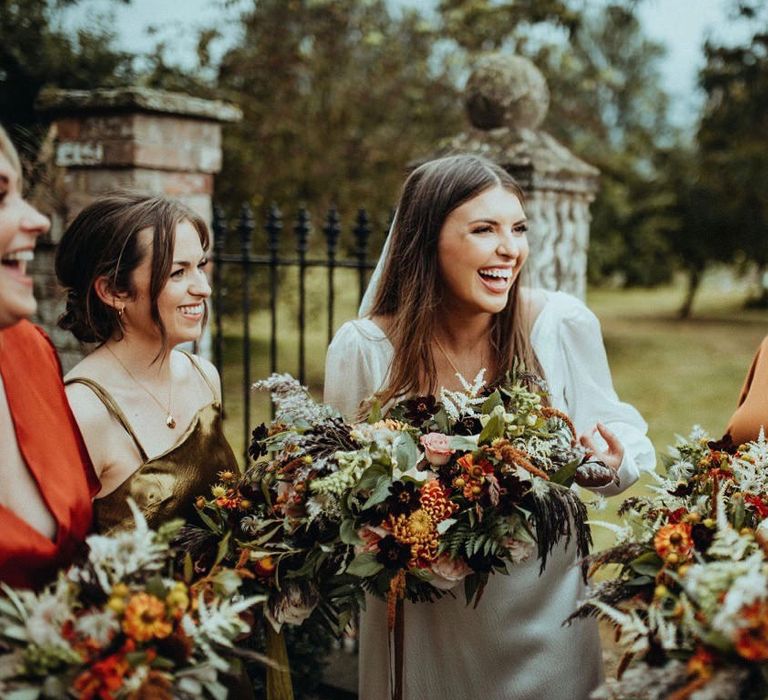 Bride laughs on her wedding day whilst holding bright floral bouquet