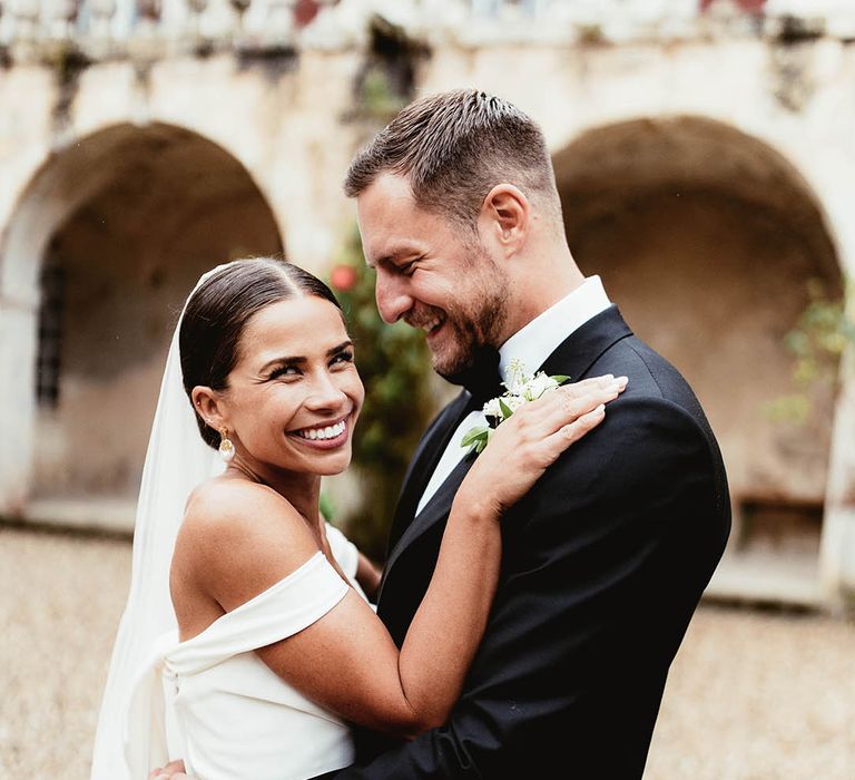 Bride & groom embrace outdoors after wedding ceremony as bride holds her hands on grooms shoulders