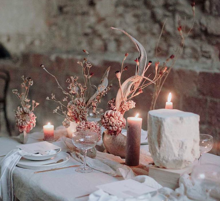 Gothic wedding table decor with natural linens, pillar candles and minimalist wedding flowers