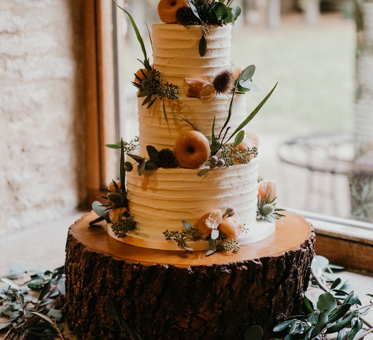 Three tier rustic wedding cake with thistle and doughnut decorations and personalised wedding cake topper