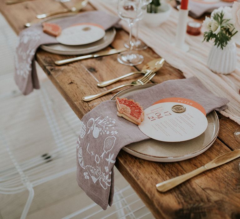 Wedding table decor at Asian wedding with taper candles, linen napkins and fan biscuit favours 