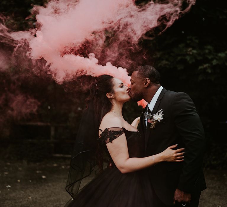 Bride & groom carry pink smoke bomb