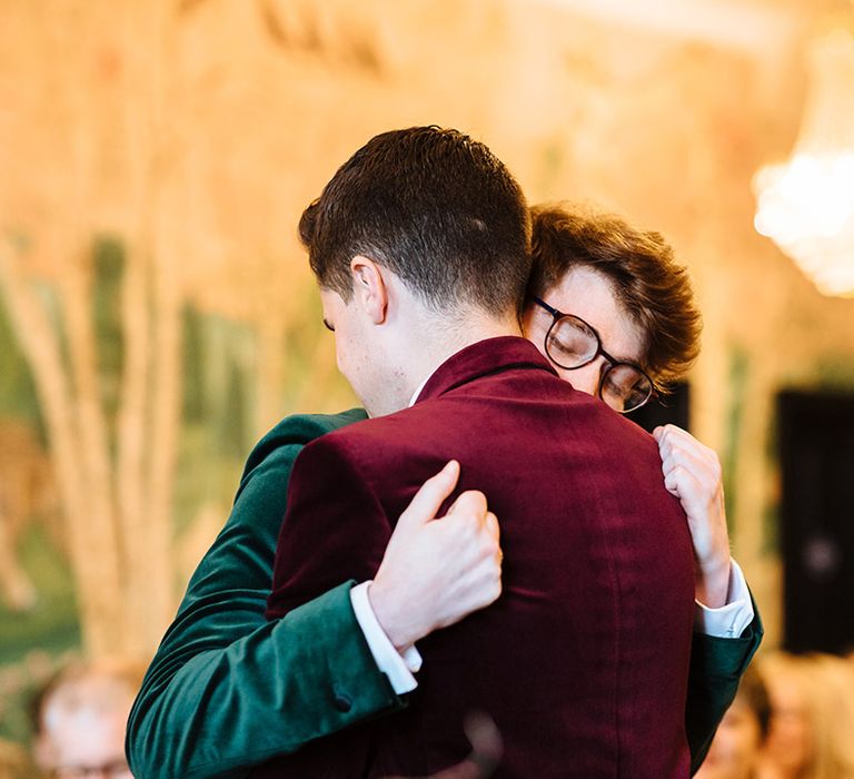 Grooms share a warm embrace on their wedding day 