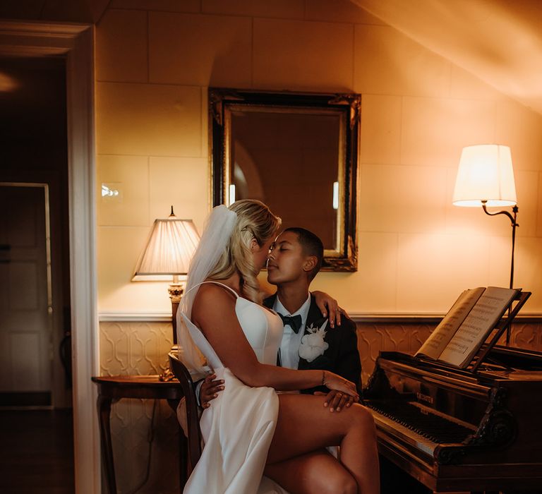 Bride in a side split wedding dress with pearl peep toe shoes sitting on her partners lap at a piano 