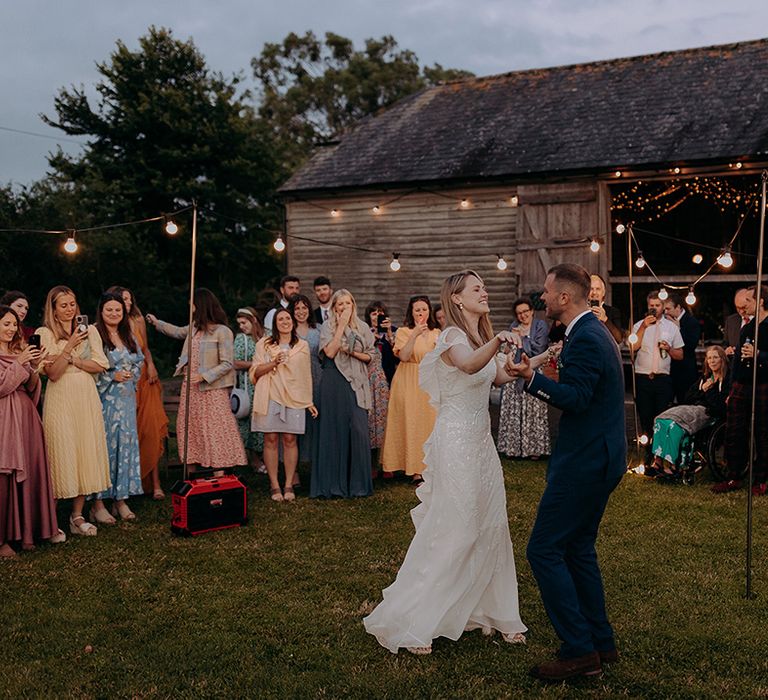 Bride and groom have their first dance together as the guests gather round and look at the couple