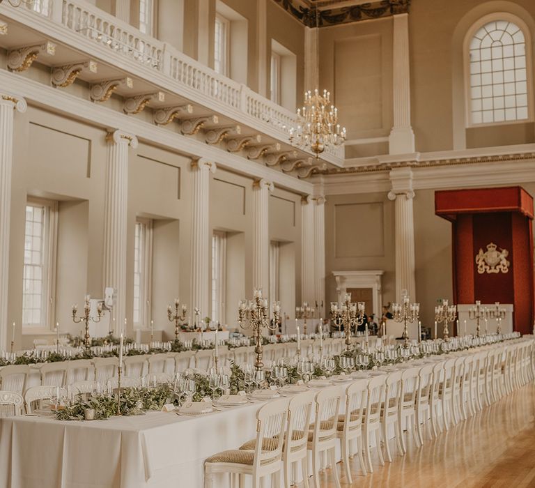 Luxury Banqueting House with gold chandeliers, white banquet tables and large gold candelabras for table decor