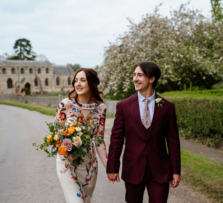 Bride and groom walk around their venue holding hands 