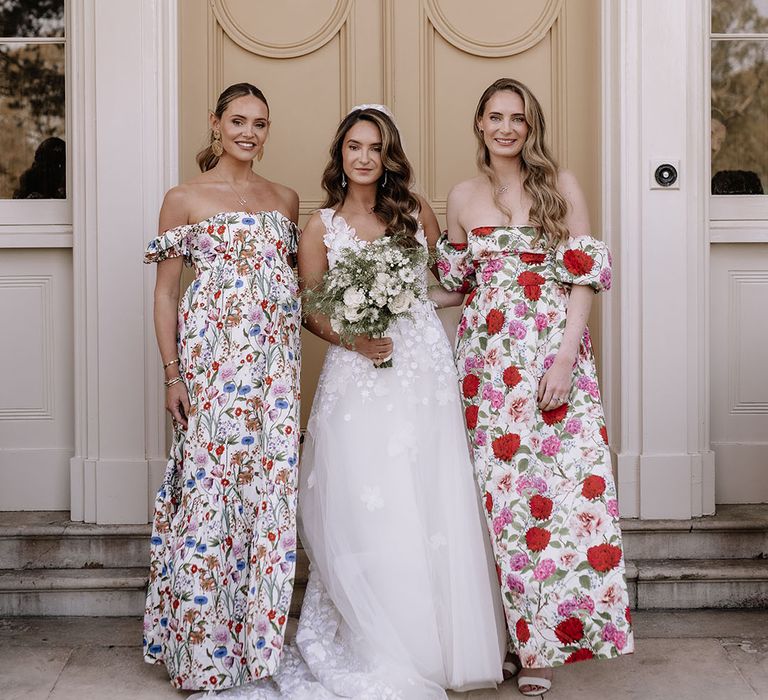 Bride in floral applique wedding dress with white bouquet with bridesmaids in flower print dresses 