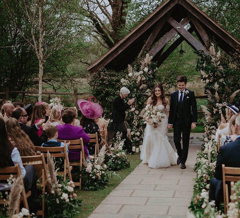 Bride and groom exit the outdoor ceremony after they're married 