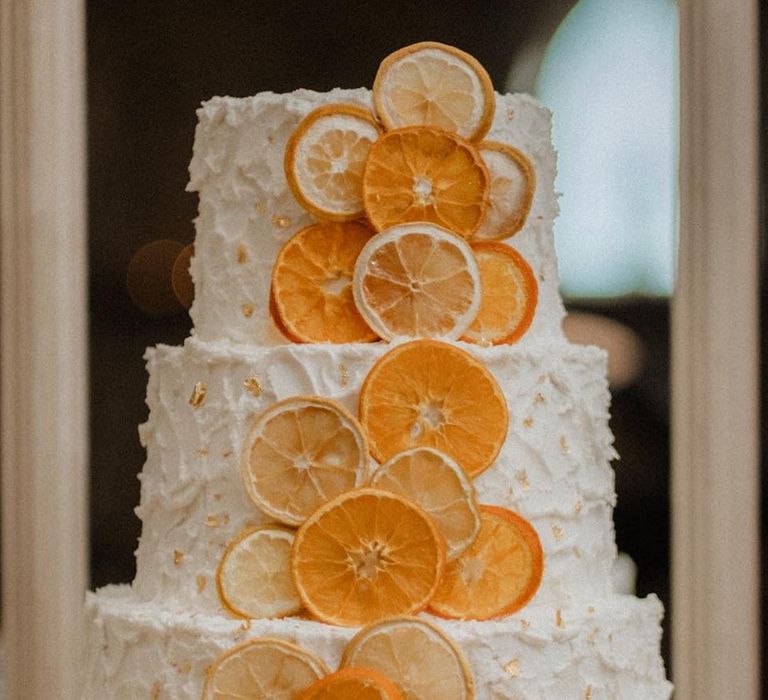 Three tier white iced vegan wedding cake with orange slice decoration 