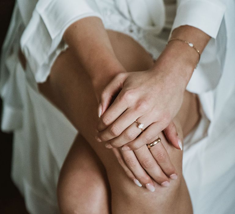 Bride wears diamond engagement ring and plain gold band complete with nude nails