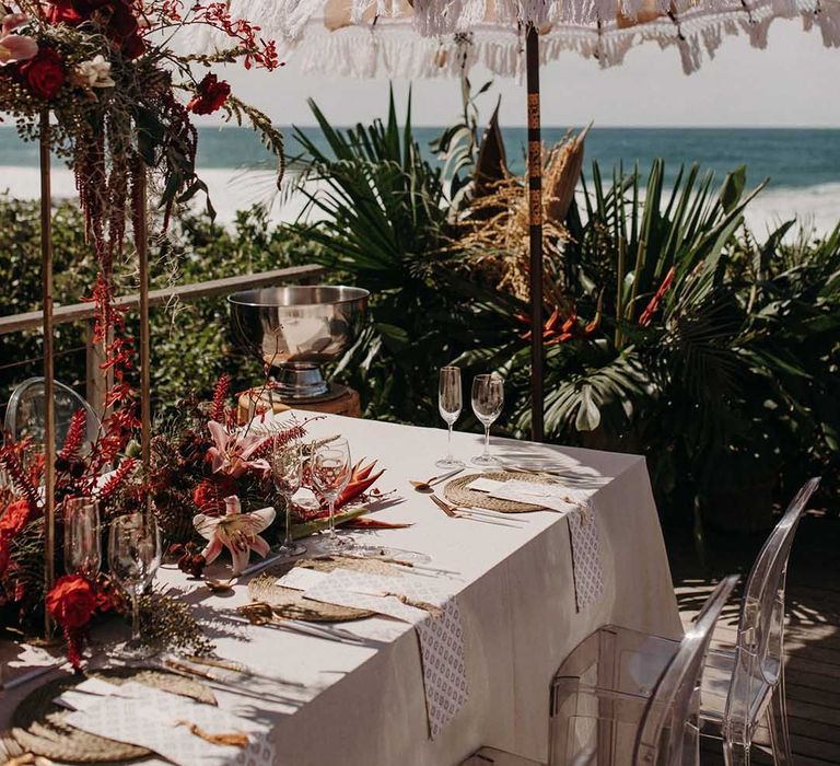 Outdoor wedding reception in South Africa complete with bright tropical florals and beach setting