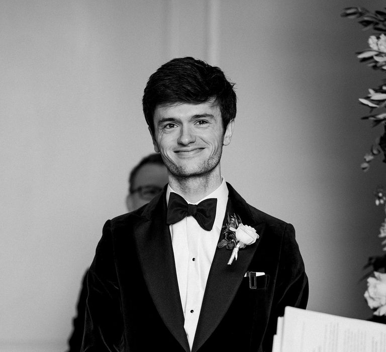 Groom wears black-tie with velvet suit jacket and rose buttonhole tied with silk ribbon 