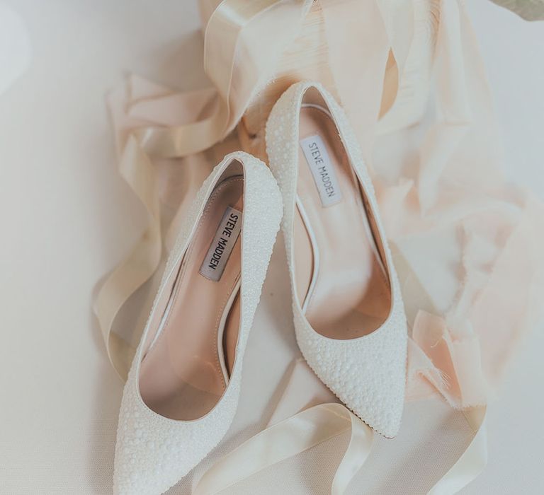 White pointed toe Steve Madden heels beside pampas grass bouquet 