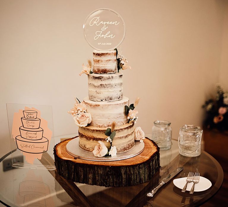 Four tier naked wedding cake with white frosting and floral decor 